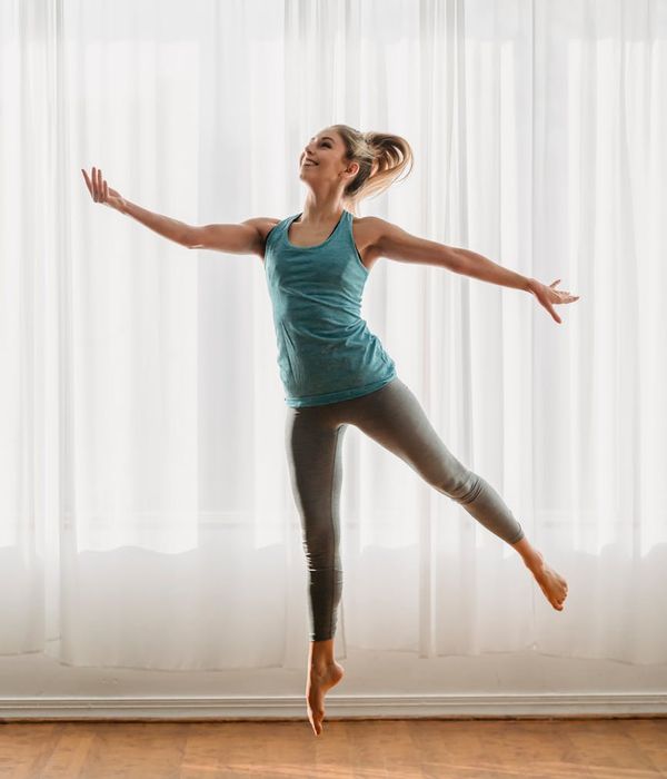 Woman performing a gentle yoga stretch in a bright room.